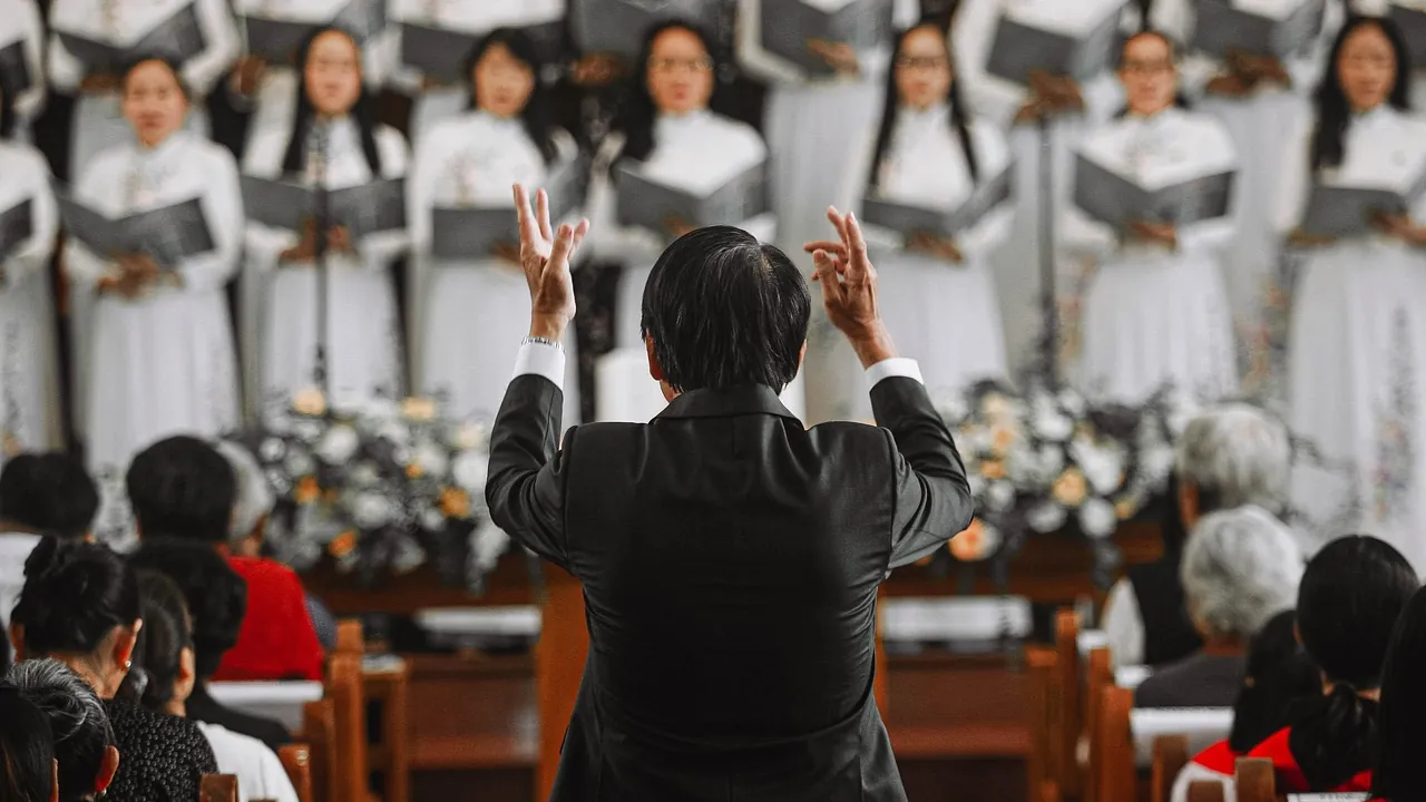 Chef de chœur, bras levés, face à une chorale