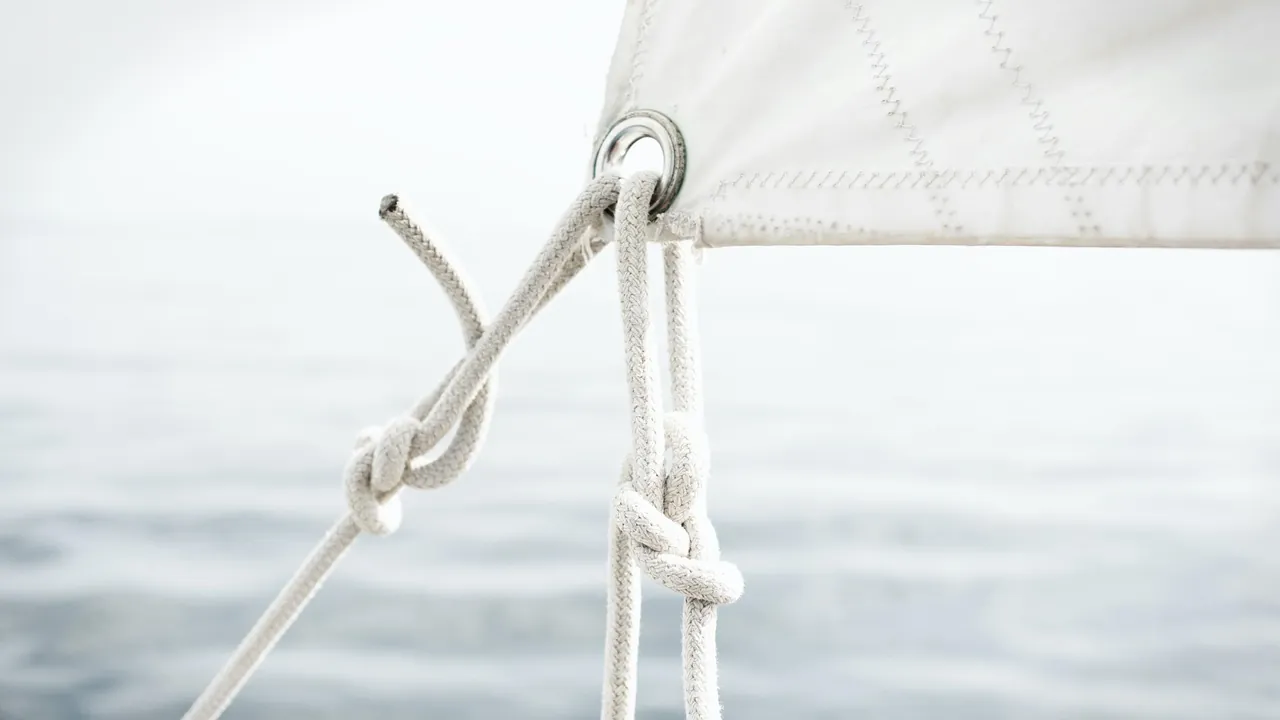 Voile et cordage noué sur un voilier, la mer en arrière-plan