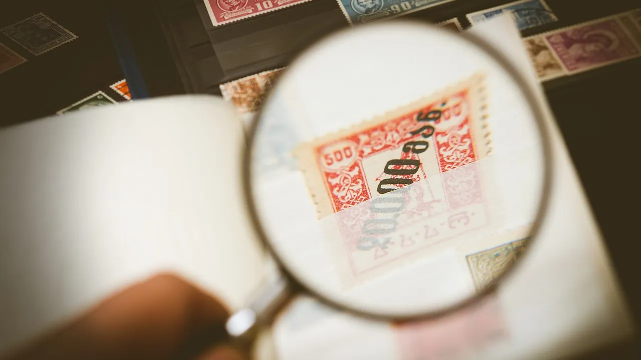 Loupe tenue au-dessus d’un timbre pour en lire les détails