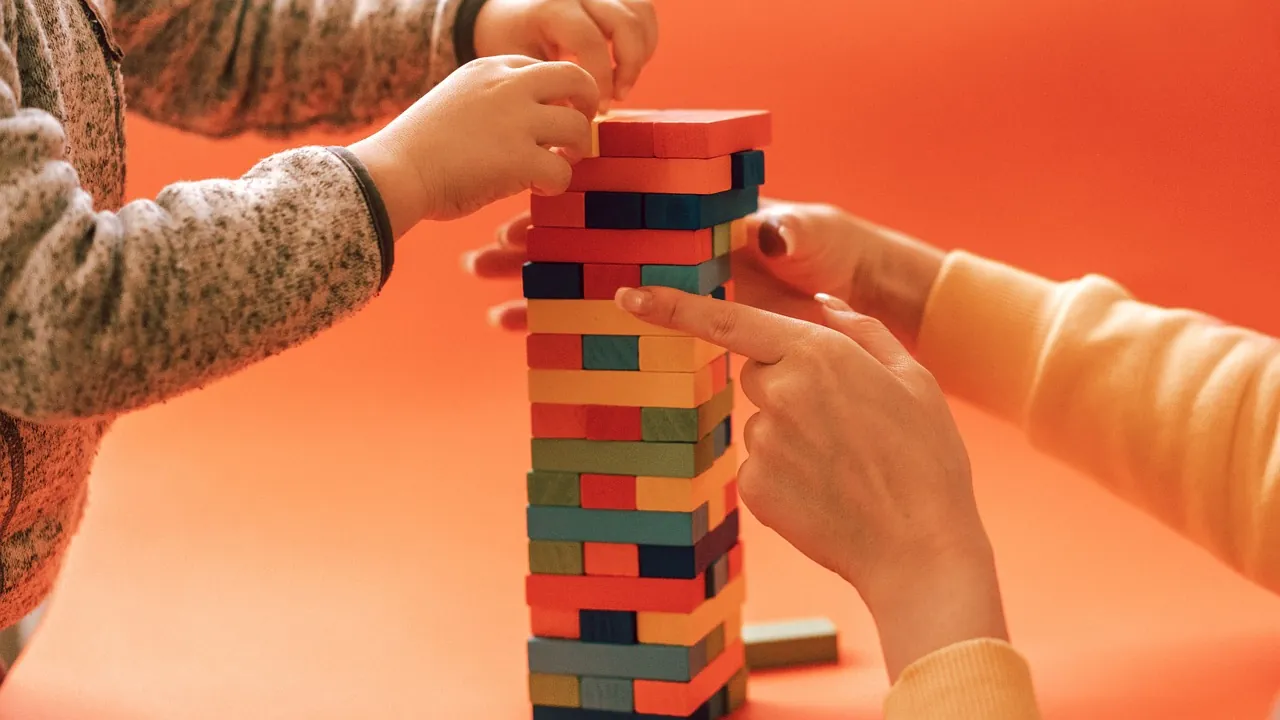 Plusieurs mains qui montent ensemble une tour de blocs de bois